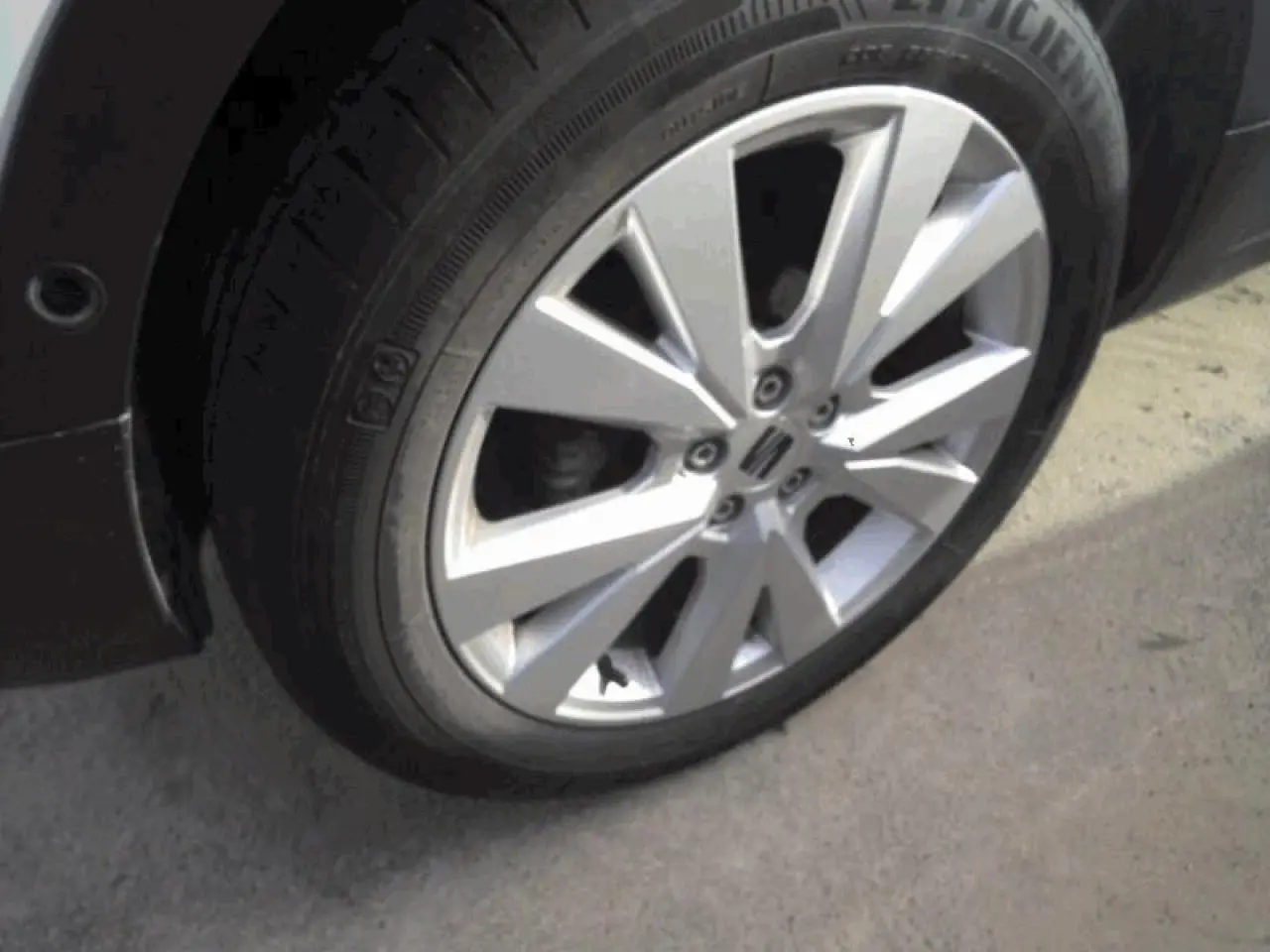 Gros plan sur la jante alliage 17'' « Dynamic » d’un SEAT Arona blanc Nevada, avec pneu visible sur sol gris.