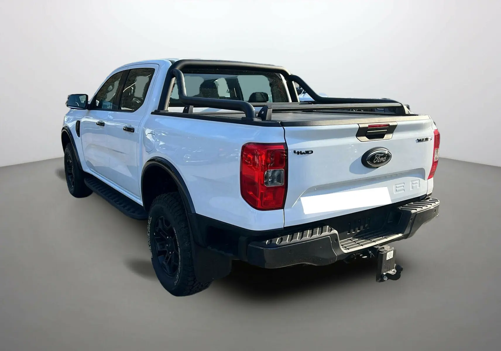 Ford Ranger blanc glacier vu 3/4 arrière droit, avec arceaux noirs et attelage visible sur fond neutre.