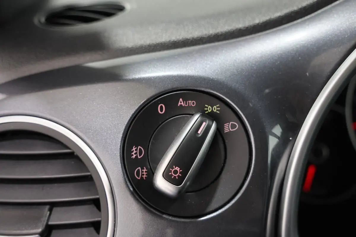 Gros plan sur le bouton de commande des phares du tableau de bord gris de la Volkswagen Coccinelle 2016.
