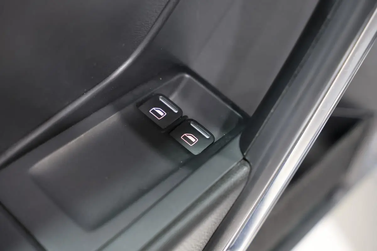 Gros plan sur les boutons de commande des vitres électriques côté conducteur d'une Volkswagen Coccinelle gris 2016.