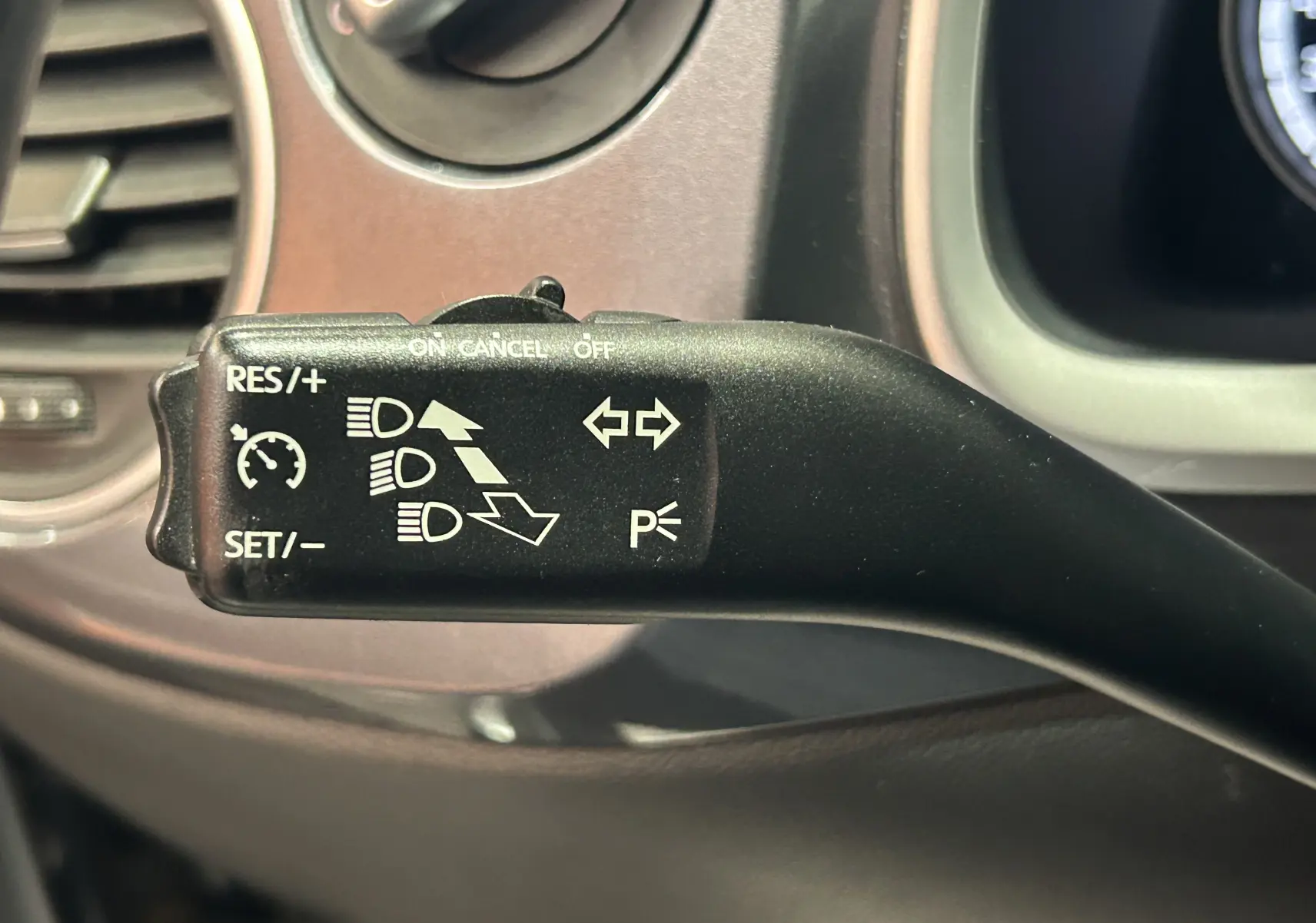 Gros plan sur la commande de régulateur de vitesse et clignotants dans l’habitacle gris d’une Volkswagen Coccinelle 2016.