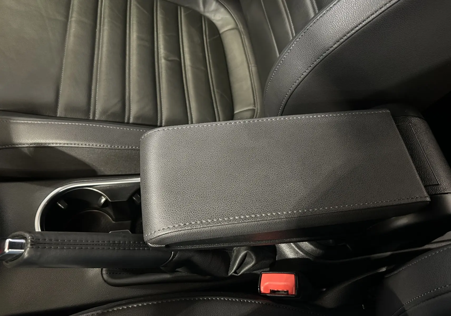 Gros plan intérieur sur l'accoudoir en cuir noir et le frein à main de la Volkswagen Coccinelle 2016.