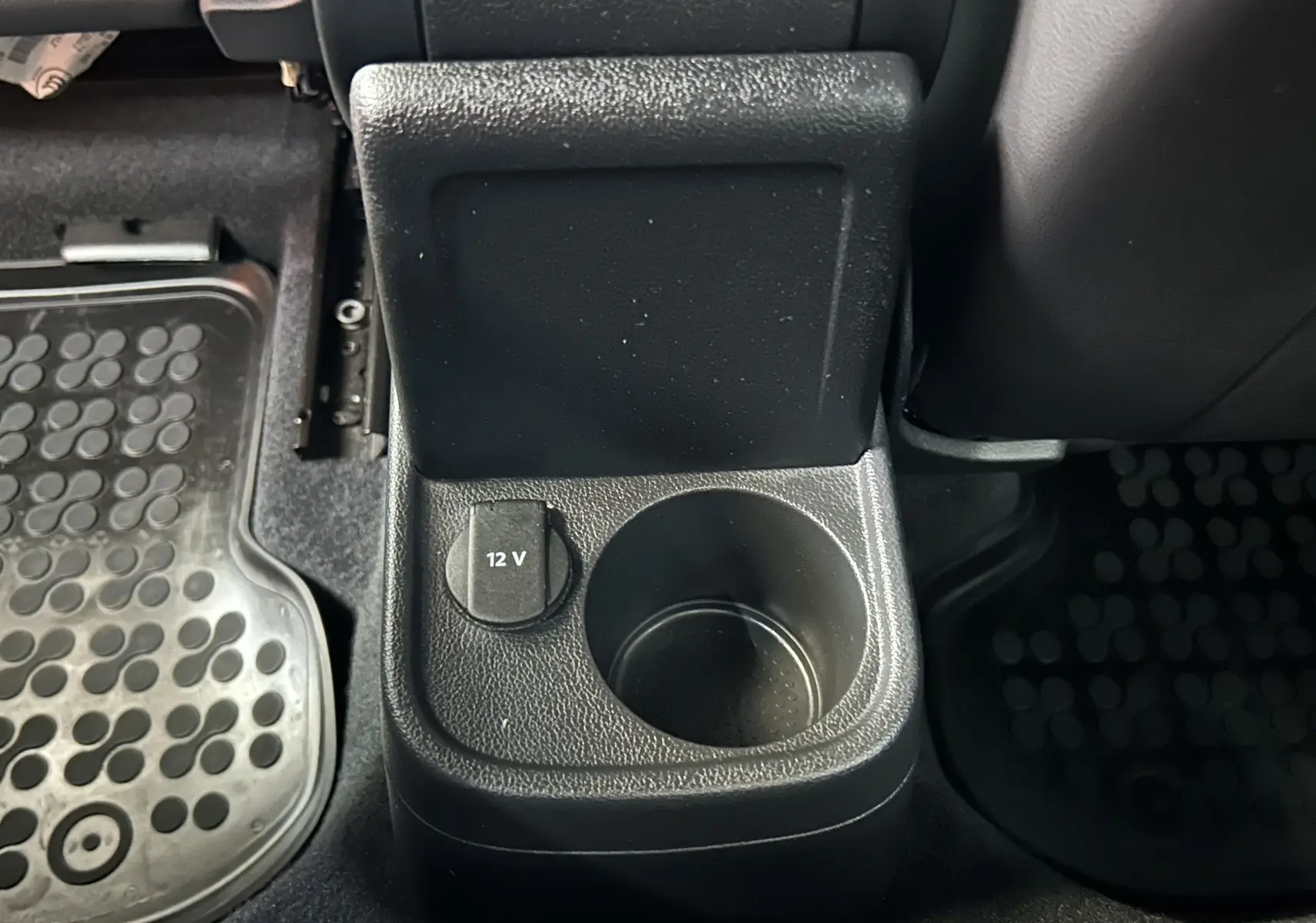 Gros plan sur la console centrale arrière noire de la Volkswagen Coccinelle gris, avec prise 12V et porte-gobelet.
