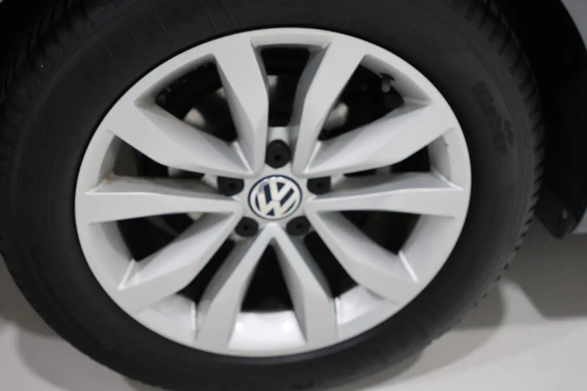 Gros plan sur la jante alliage argentée avec logo Volkswagen au centre d’une Volkswagen Coccinelle gris 2016.