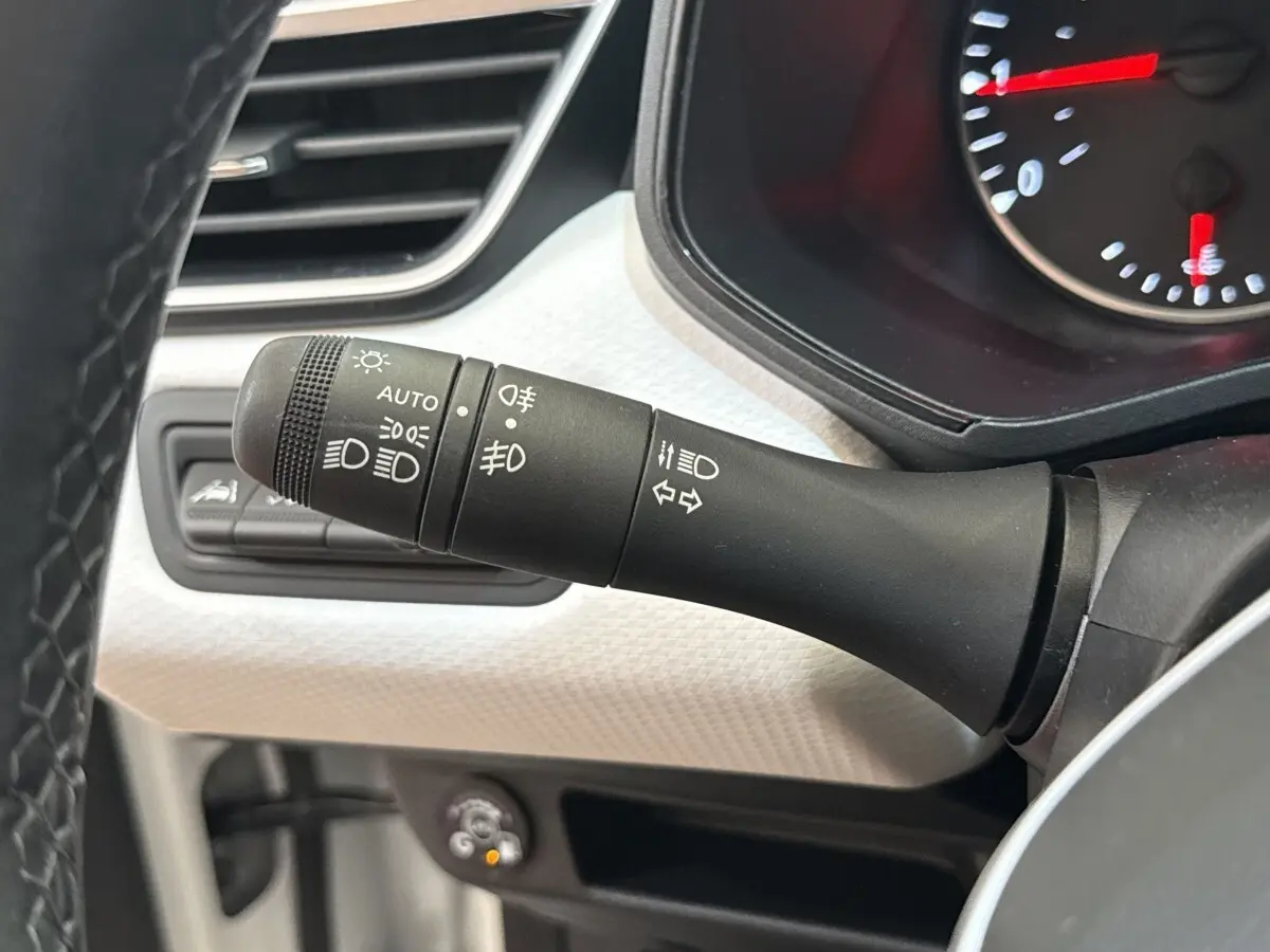 Gros plan sur la commande des phares et clignotants dans l’habitacle blanc de la Renault Clio Evolution TCe 100 GPL 2023.