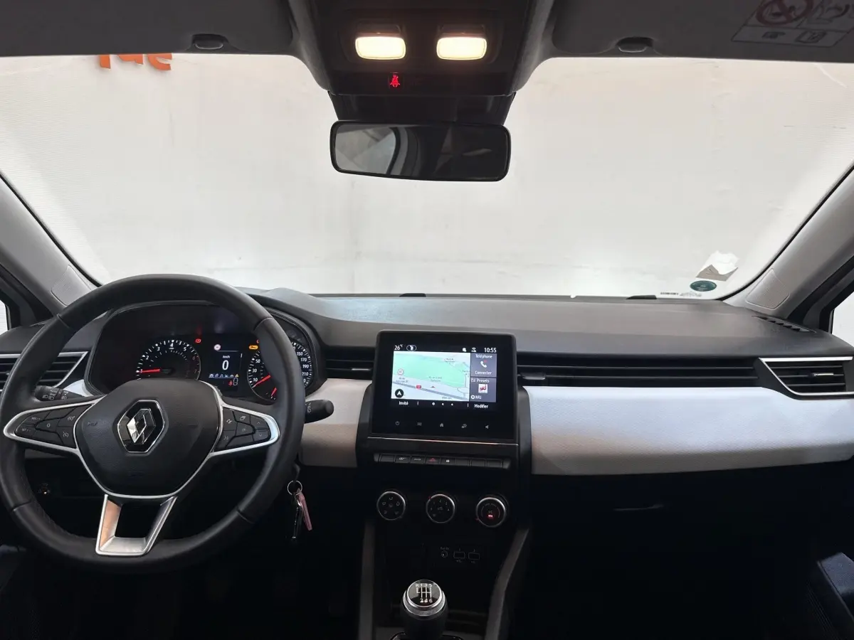 Vue intérieure avant de la Renault Clio blanche 2023, avec tableau de bord moderne et écran tactile central.