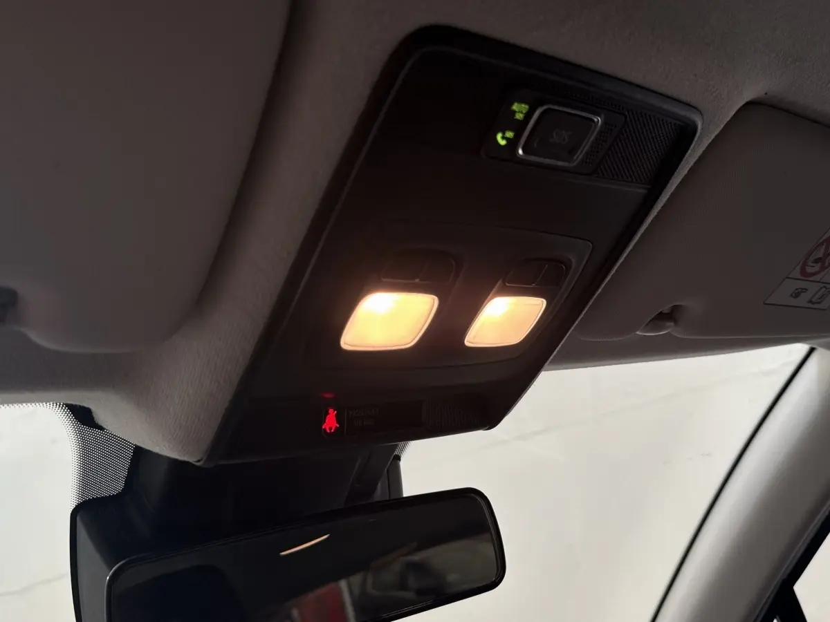 Plafonnier intérieur allumé vu de dessous avec miroir de courtoisie et panneau de commande noir dans une Renault Clio blanche.