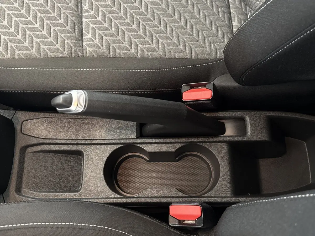 Vue plongeante sur le frein à main et porte-gobelets centraux de la Renault Clio Evolution TCe 100 GPL, intérieur noir.