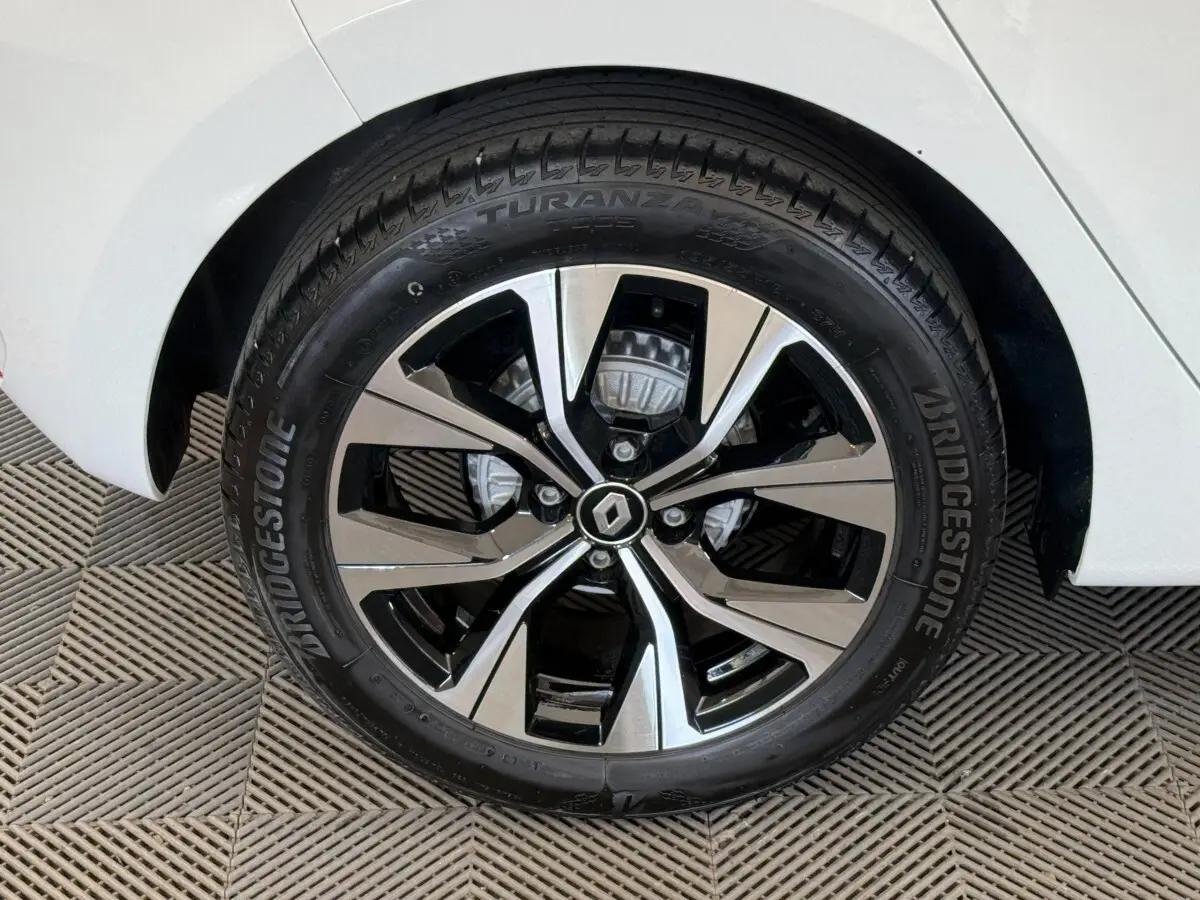 Gros plan sur la roue avant droite d'une Renault Clio blanche, jante alliage bicolore avec logo Renault central.