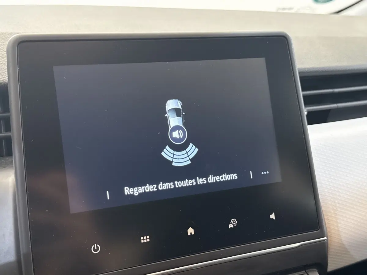 Écran tactile central de la Renault Clio blanche 2023 affichant l'alerte de surveillance tous angles.