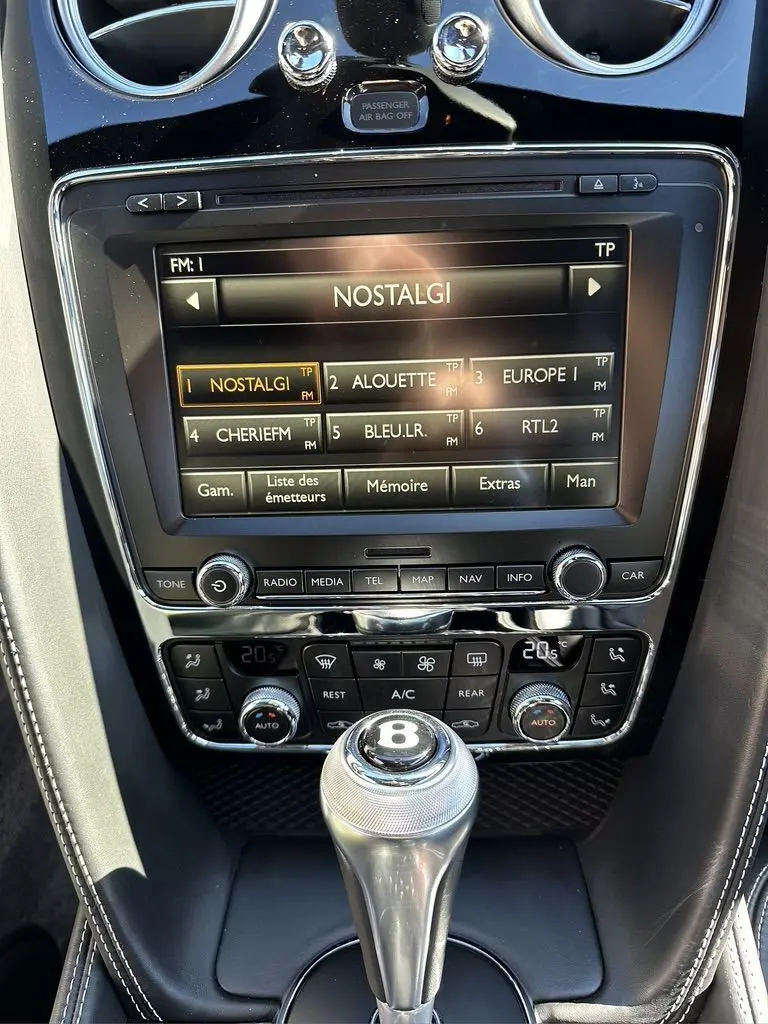 Gros plan sur la console centrale noire de la Bentley Continental GT II avec écran tactile et levier de vitesse marqué du logo Bentley.