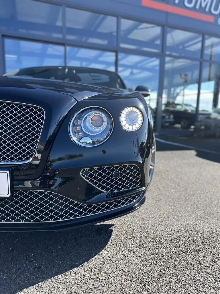 Gros plan sur l'avant droit noir brillant d'une Bentley Continental GT Speed 2015 avec ses phares ronds LED distinctifs.