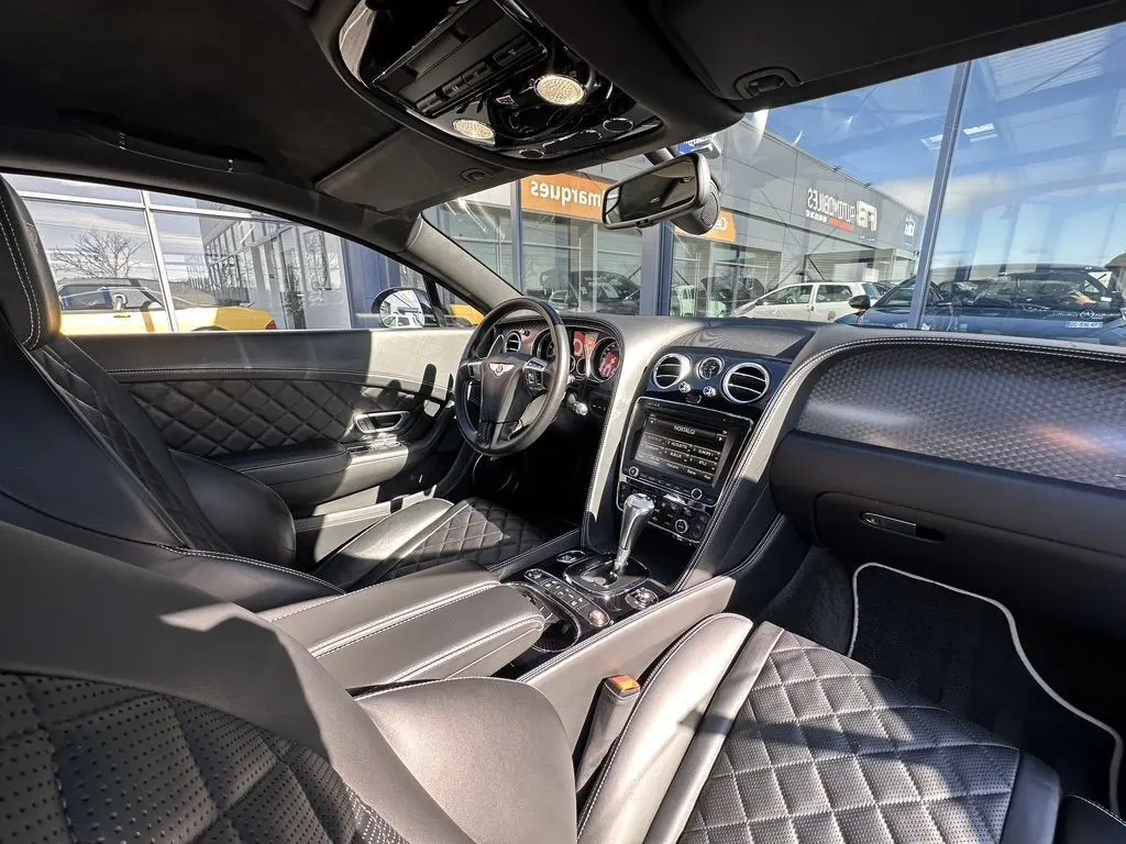 Intérieur noir de la Bentley Continental GT II 2015, vue côté conducteur, cuir matelassé et tableau de bord élégant.