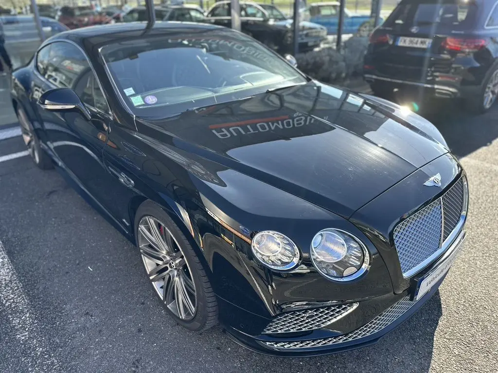 Bentley Continental GT Speed noire vue en 3/4 avant droit, mettant en valeur sa calandre et ses phares ronds distinctifs.