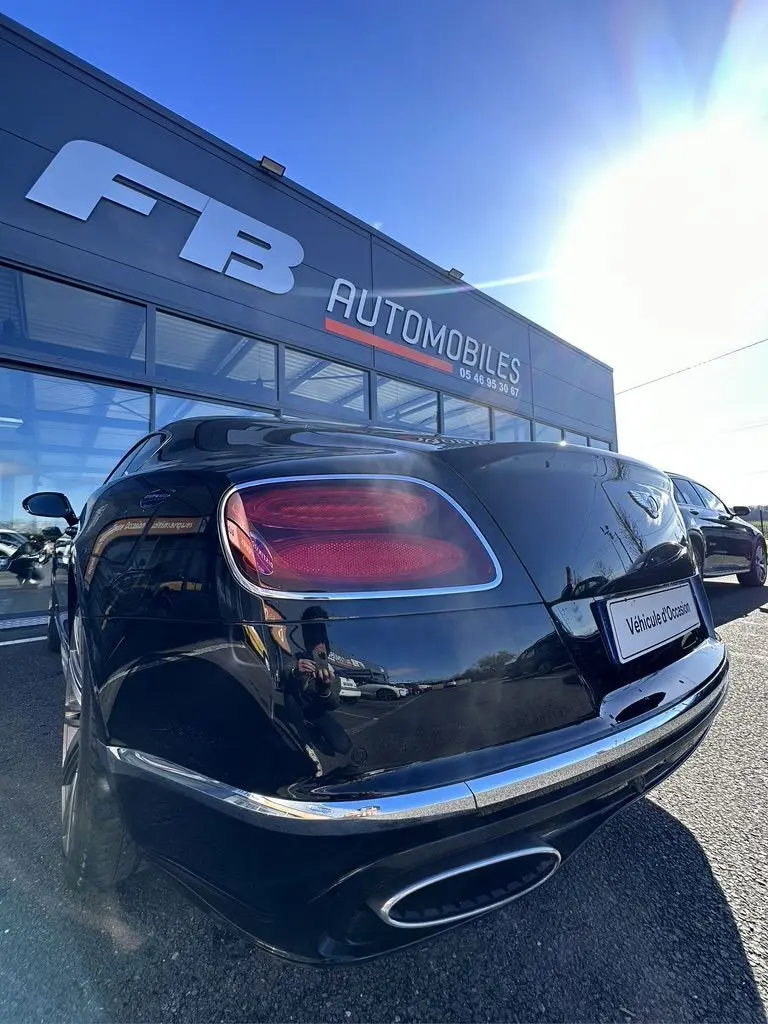 Vue 3/4 arrière droite d'une Bentley Continental GT Speed noire 2015 avec feux arrière ovales et double sortie d'échappement chrome.