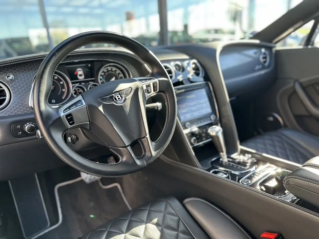 Intérieur noir de la Bentley Continental GT Speed 2015, vue du poste de conduite avec volant et console centrale en cuir.