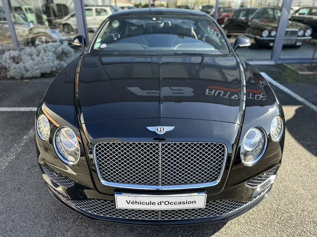 Vue avant rapprochée d'une Bentley Continental GT Speed noire de 2015 avec calandre chromée et phares ronds.