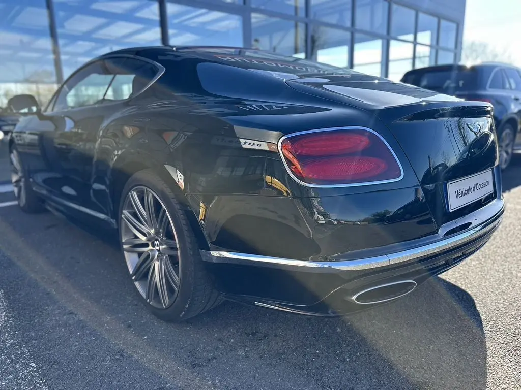 Bentley Continental GT Speed noire vue 3/4 arrière droit, avec feux rouges et jantes alliage distinctives.