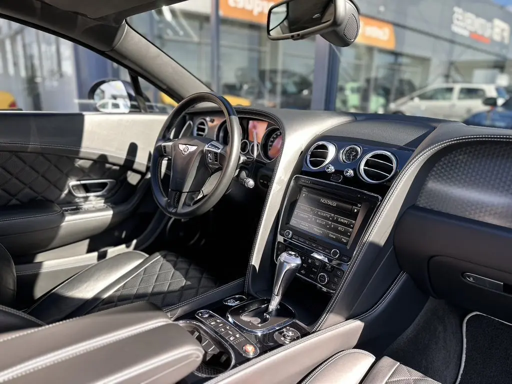 Intérieur cuir noir matelassé de la Bentley Continental GT Speed 2015, vue côté conducteur avec tableau de bord et console centrale.