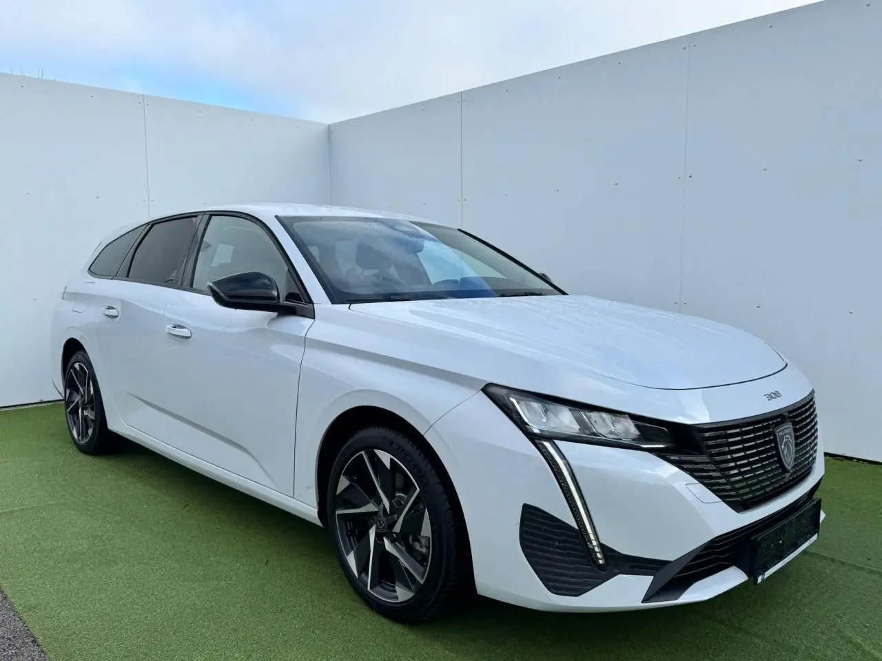 Peugeot 308 SW blanc Okenite vue 3/4 avant droit avec calandre noire et jantes alliage 17 pouces Halong diamantées.