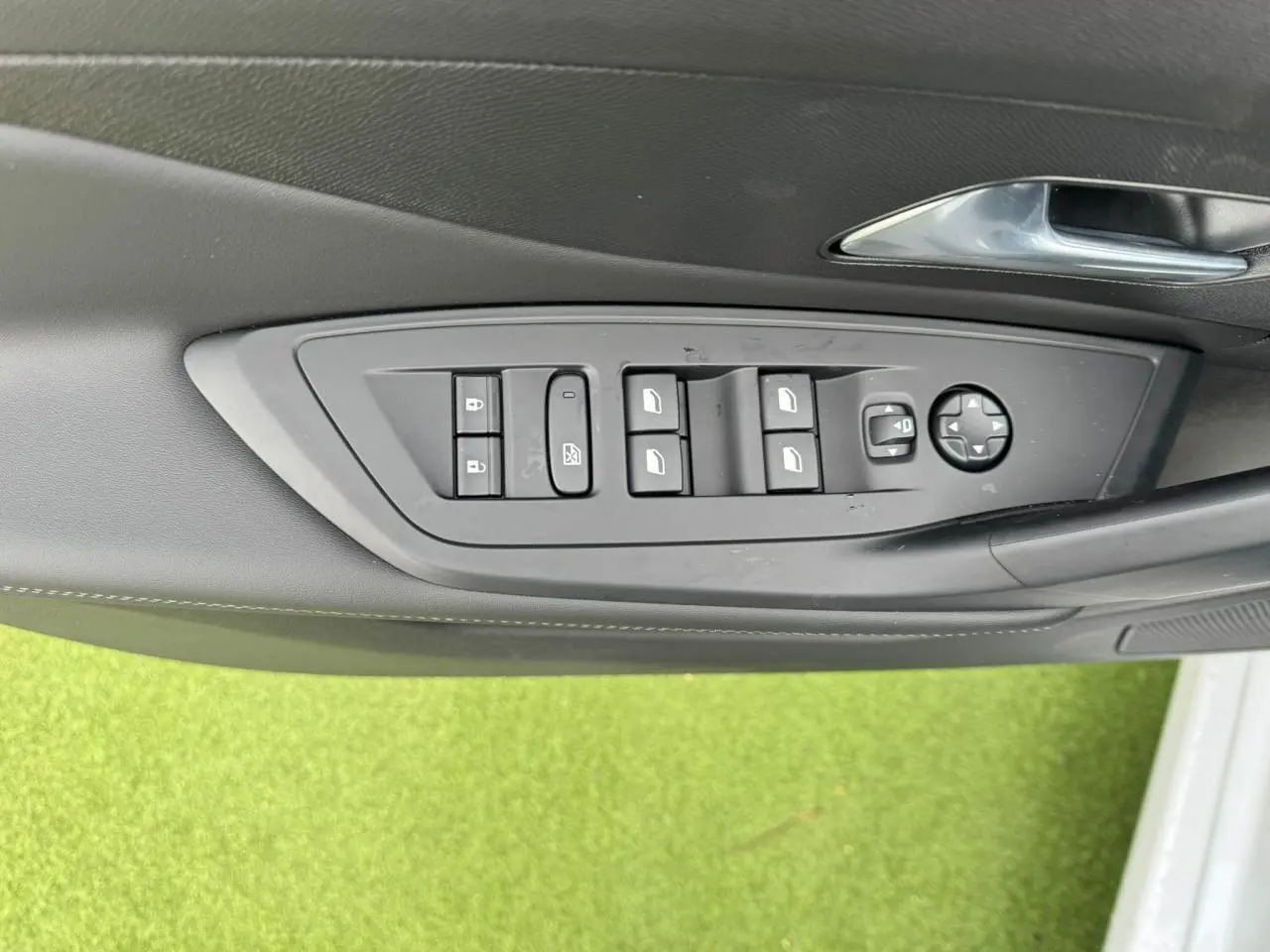 Panneau de commandes des vitres et rétroviseurs côté gauche intérieur d'une Peugeot 308 SW blanche 2024