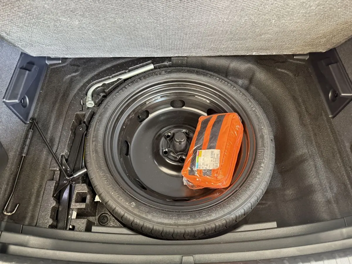 Vue rapprochée du coffre du SEAT Ateca 2023 montrant la roue de secours noire et un kit de sécurité orange.