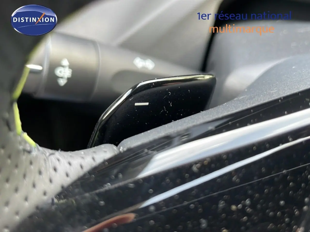 Gros plan sur la palette de changement de vitesse noire côté droit du volant perforé dans une Peugeot 308 gris Artense.