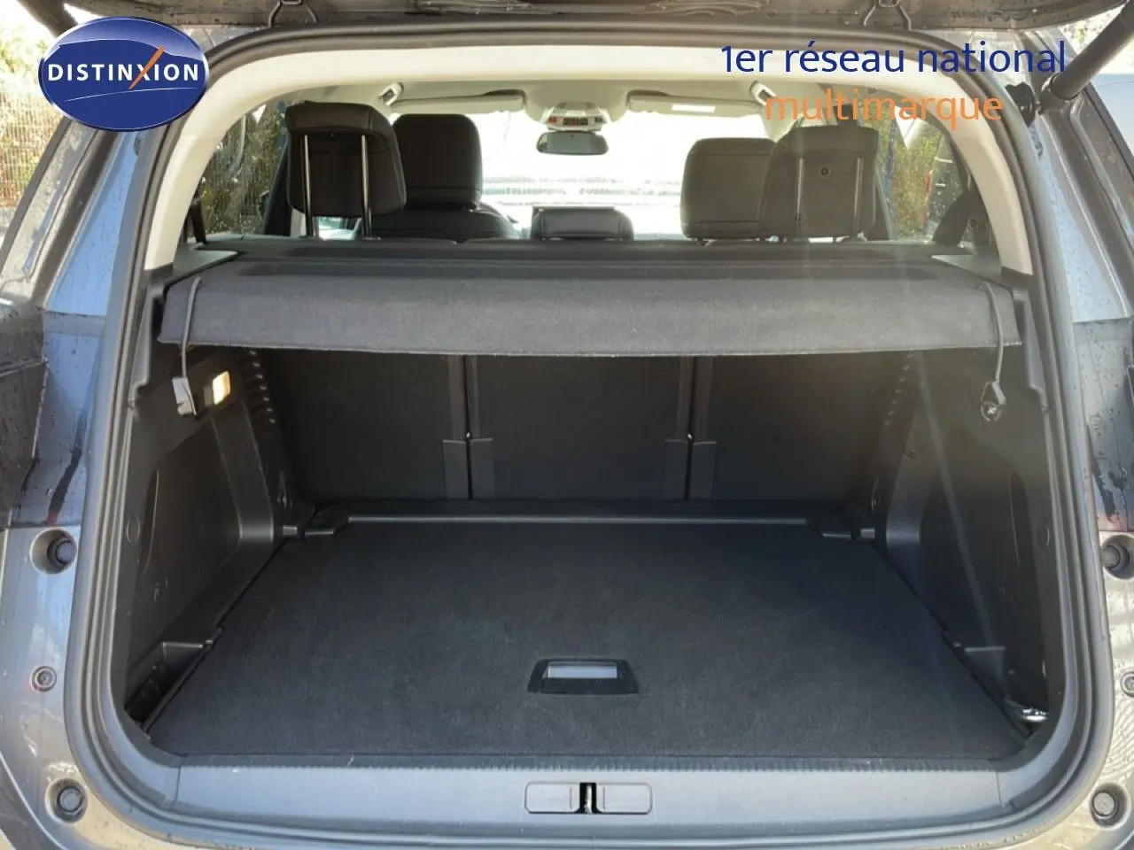 Coffre ouvert vu de l'arrière d'un Citroën C5 Aircross gris platinium métal avec banquette arrière et cache-bagages visibles.