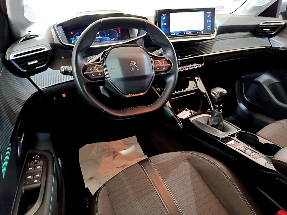 Intérieur de la Peugeot 208 PureTech 100 S&S Allure Business 2020, vue cockpit côté conducteur avec volant cuir et écran tactile.