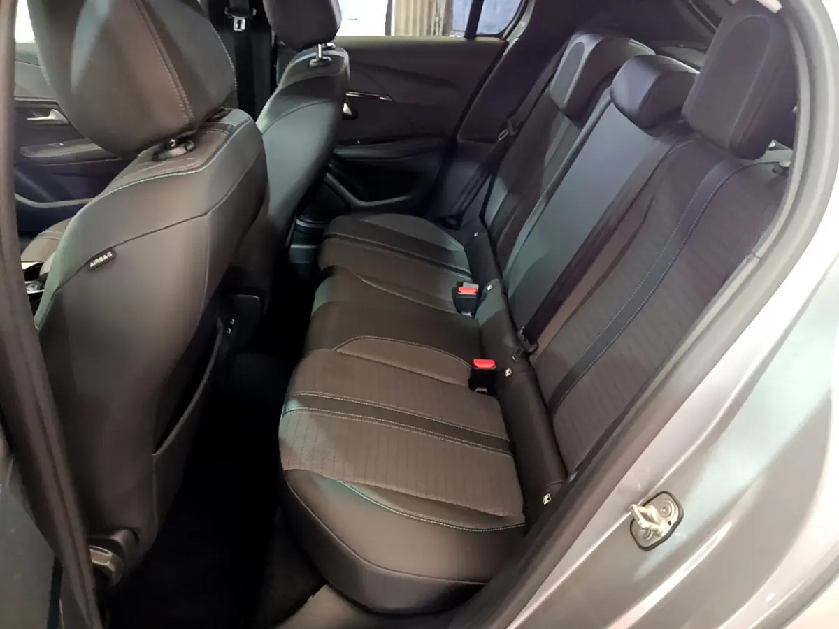 Vue côté droit sur l'intérieur arrière gris foncé de la Peugeot 208 2020 avec sièges en tissu et cuir et ceintures rouges.