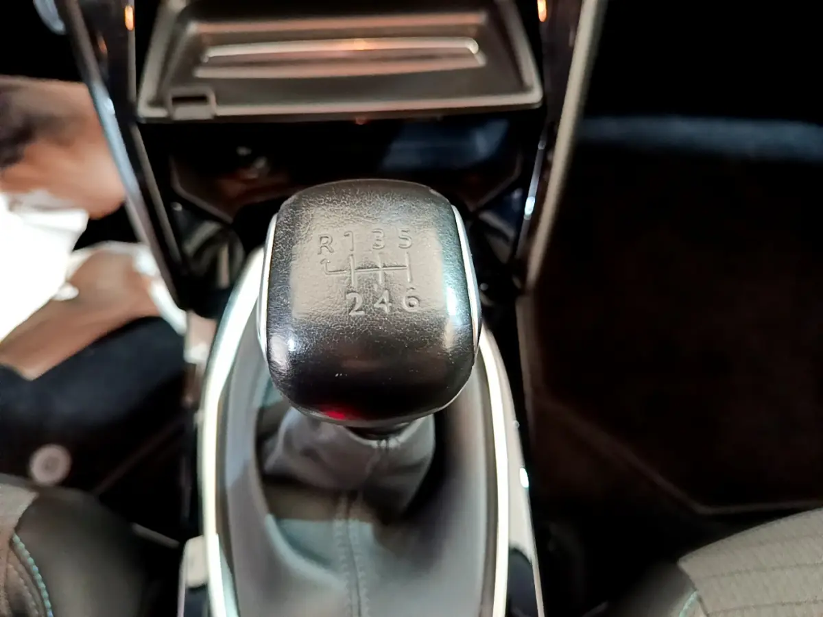 Le levier de vitesses manuel noir de la Peugeot 208 PureTech 100 S&S Allure Business, vue rapprochée intérieure.