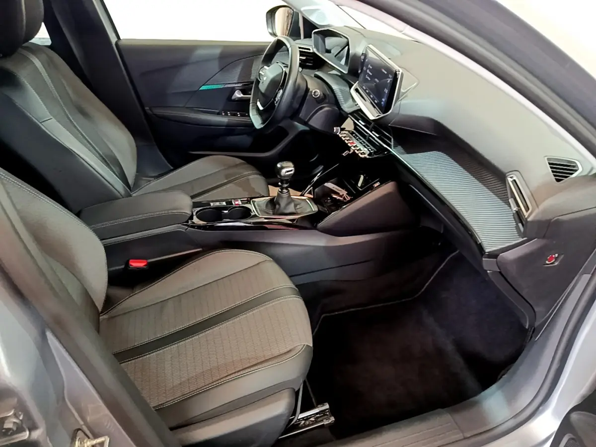 Intérieur avant droit de la Peugeot 208 gris clair 2020 avec tableau de bord moderne et boîte manuelle.