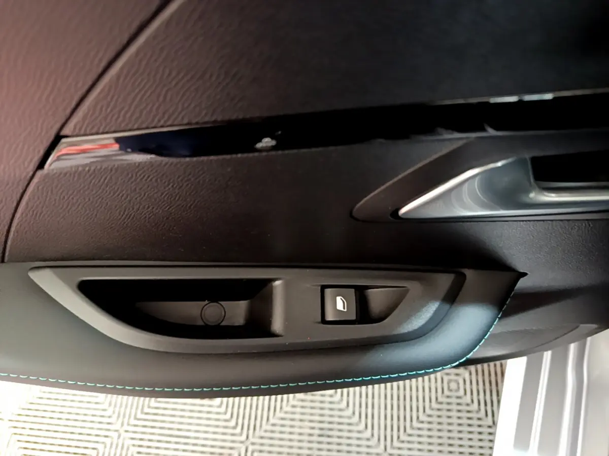 Détail de la poignée intérieure et bouton de verrouillage de la porte côté gauche d'une Peugeot 208 gris clair 2020.