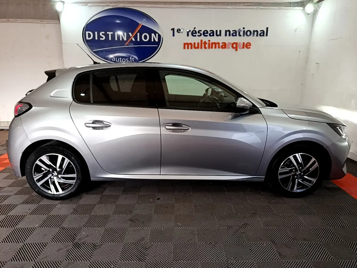 Profil côté droit d'une Peugeot 208 gris clair 2020 PureTech 100 S&S Allure Business en intérieur showroom.