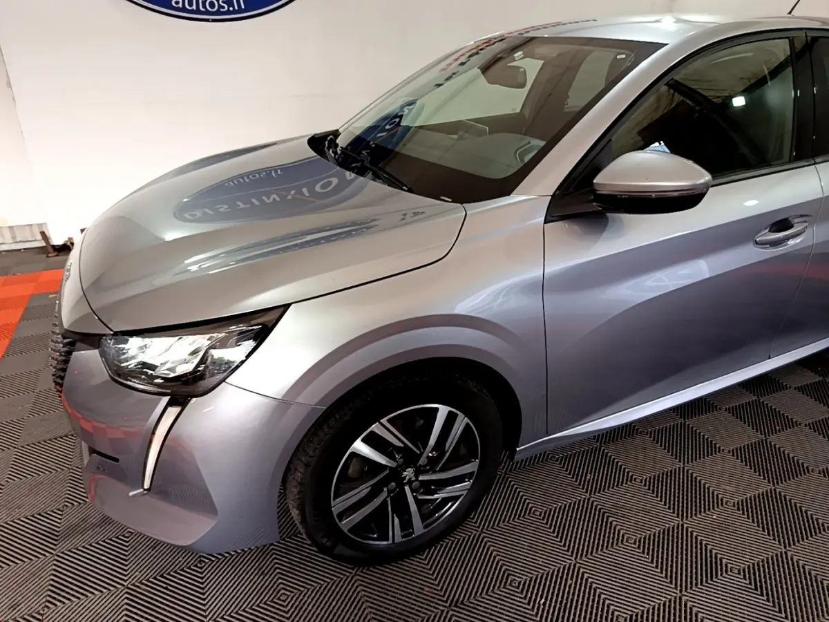 Peugeot 208 gris clair vue 3/4 avant droit, avec phares LED et jantes alliage distinctives.