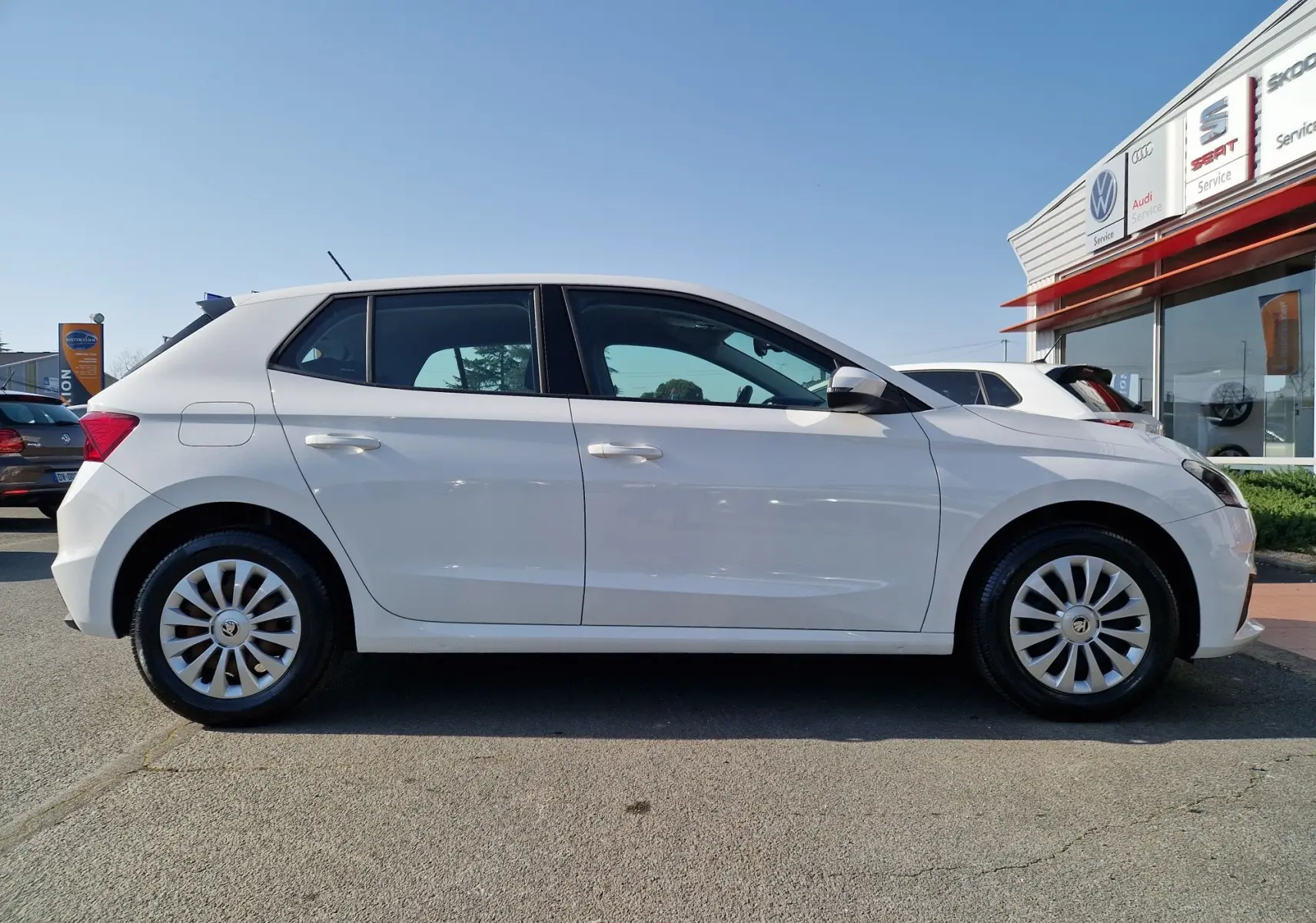 Vue de profil côté gauche d'une Skoda Fabia berline blanche 2022 avec jantes acier et enjoliveurs en concession.
