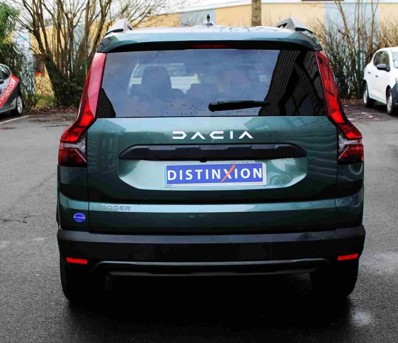 Vue arrière d'une Dacia Jogger vert cèdre métal 2025 avec logo DACIA et plaque Distinxion visible.