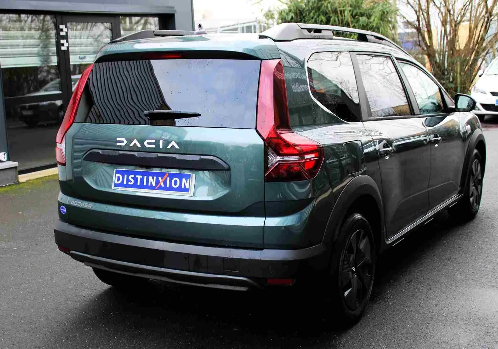 Vue 3/4 arrière droite d'un Dacia Jogger vert cèdre métal avec feux arrière en forme de C et toit noir.