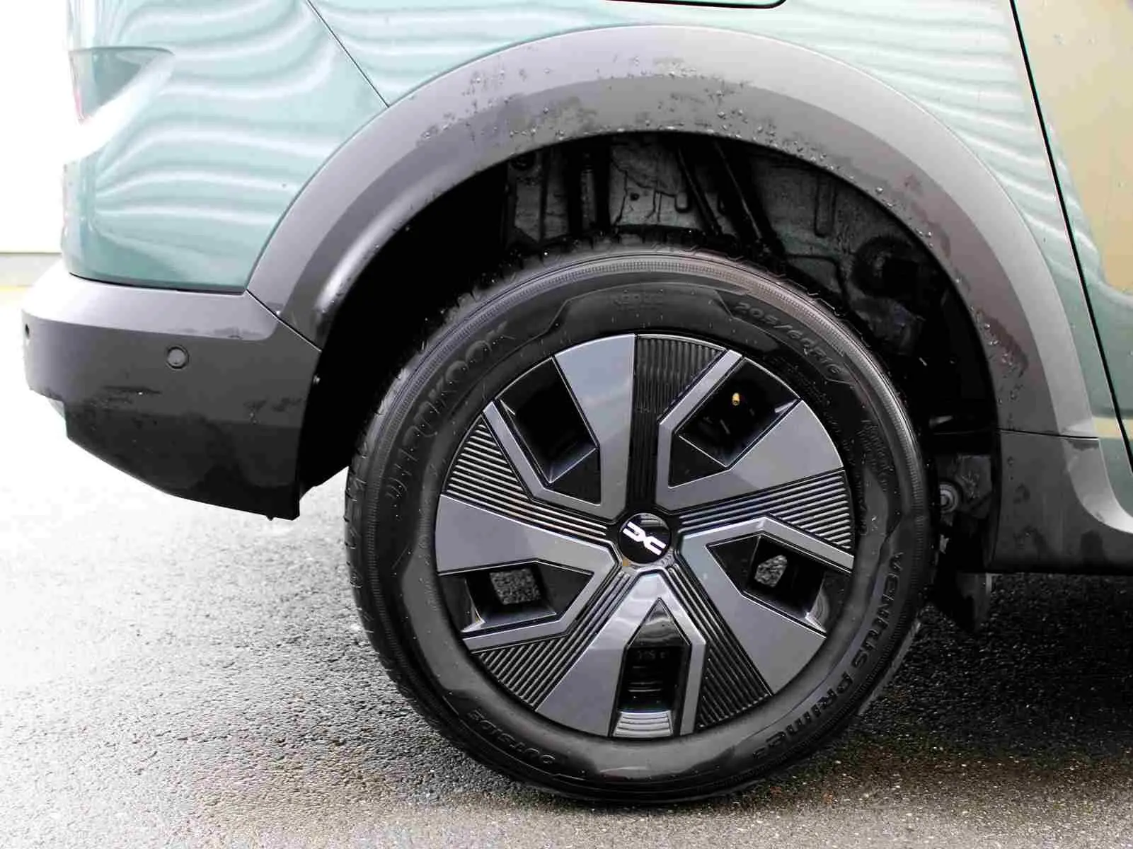 Gros plan sur la roue arrière gauche du Dacia Jogger vert cèdre métal, mettant en valeur la jante au design moderne.