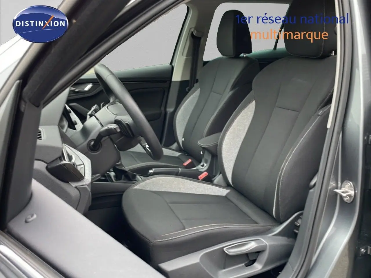 Vue intérieure côté conducteur du Skoda Kamiq 2025 gris graphite, sièges tissu noir et gris avec coutures contrastées.