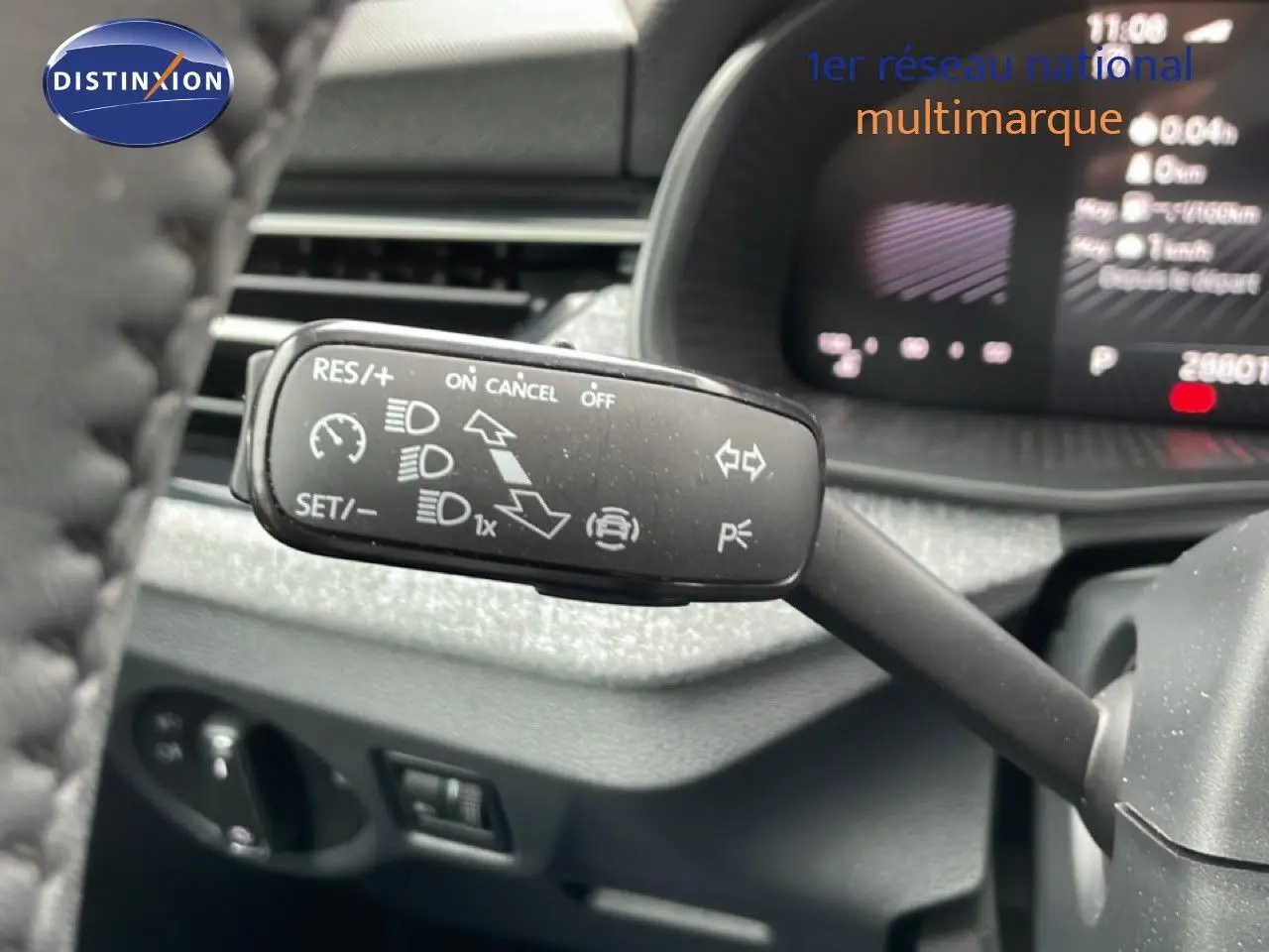Gros plan sur la commande de régulateur de vitesse du Skoda Kamiq 2025, intérieur gris graphite avec tableau de bord numérique flou.