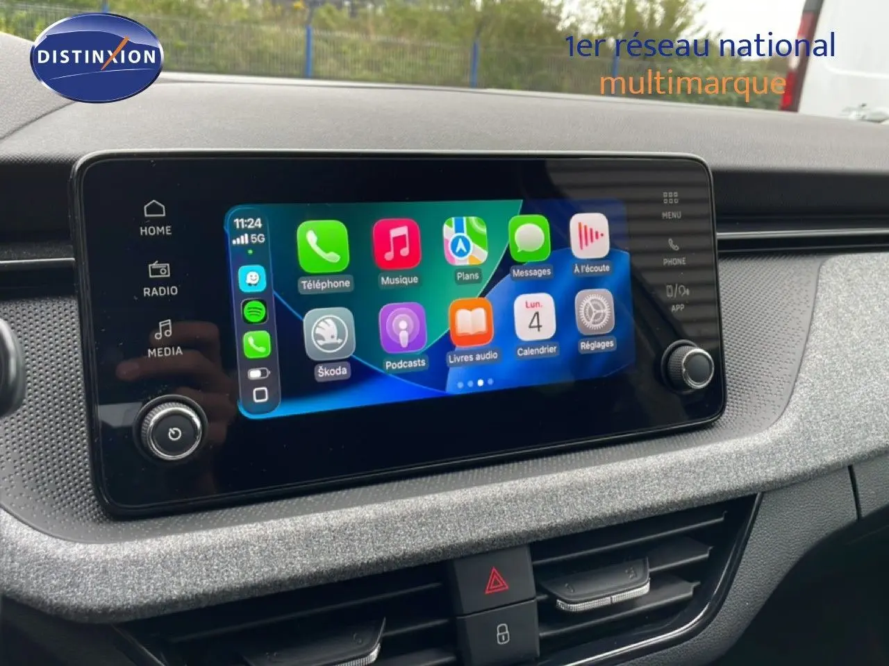 Écran tactile central du Skoda Kamiq 2025 affichant l’interface Apple CarPlay, avec tableau de bord gris texturé en arrière-plan.