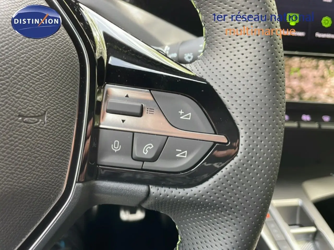 Gros plan sur les commandes au volant en cuir perforé gris foncé de la Peugeot 308 Hybrid 2026, intérieur moderne.