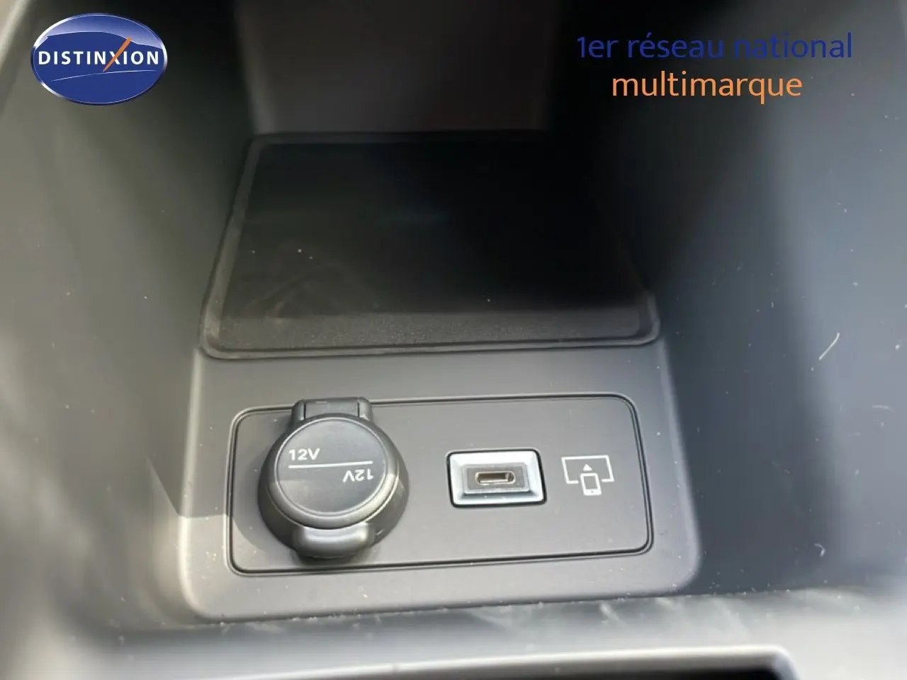 Prise 12V et port USB-C en gros plan dans le compartiment central d'une Peugeot 308 gris Artense Metal.