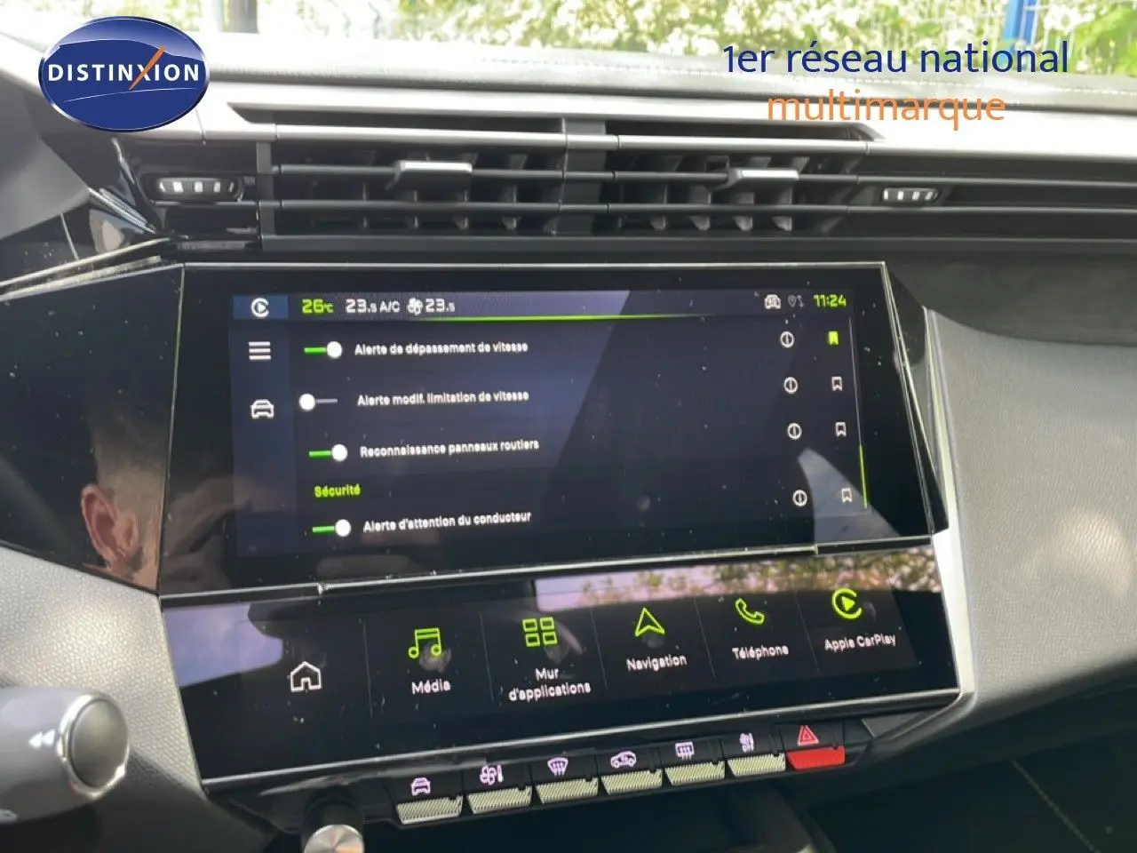 Vue rapprochée de l'écran tactile central du tableau de bord de la Peugeot 308 gris Artense, affichant les options de sécurité et multimédia.