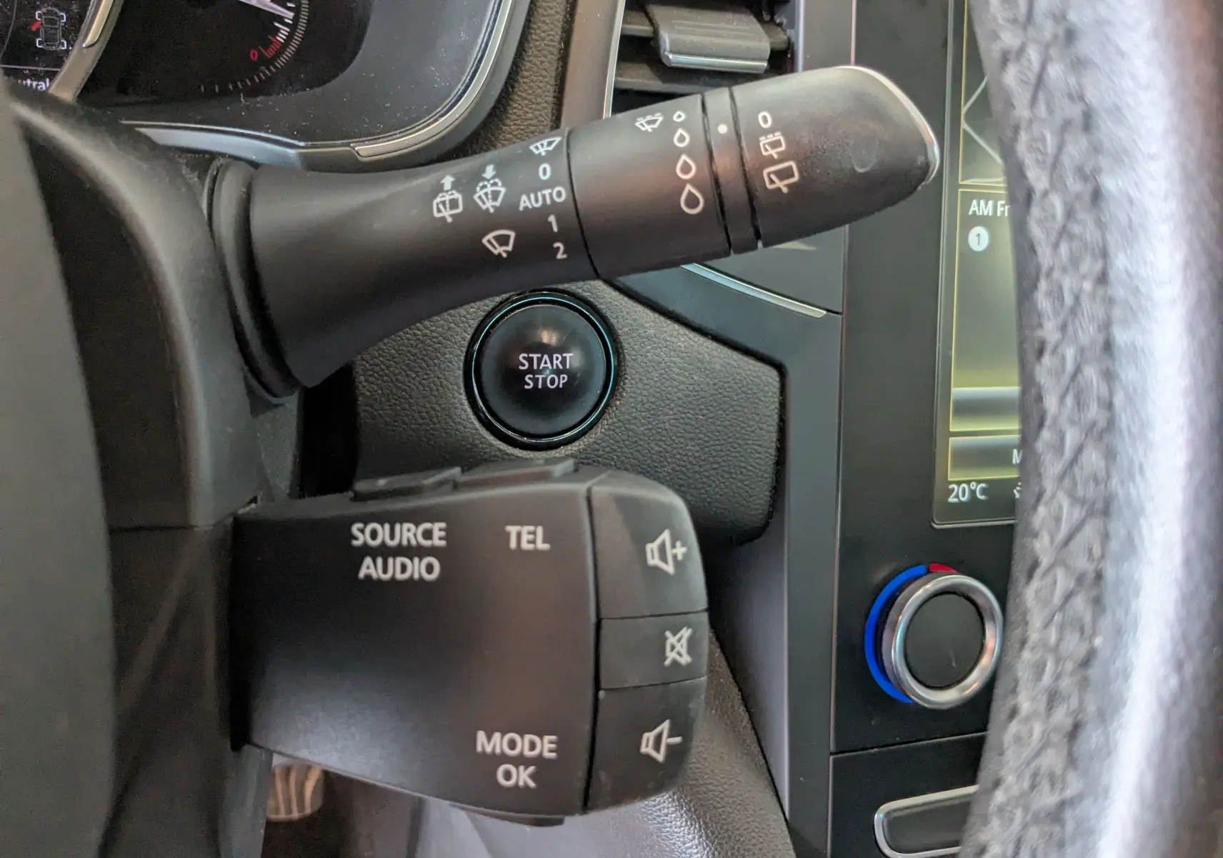 Gros plan intérieur sur la commande de phares et le bouton start/stop d'une Renault Mégane IV gris 2019.
