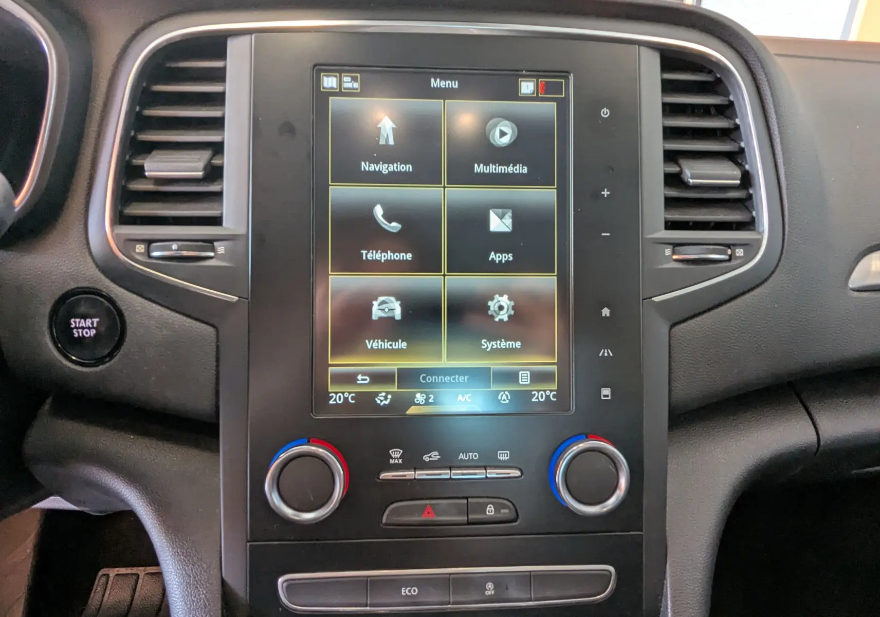 Vue rapprochée du tableau de bord de la Renault Mégane IV gris, avec écran tactile central et commandes de climatisation.