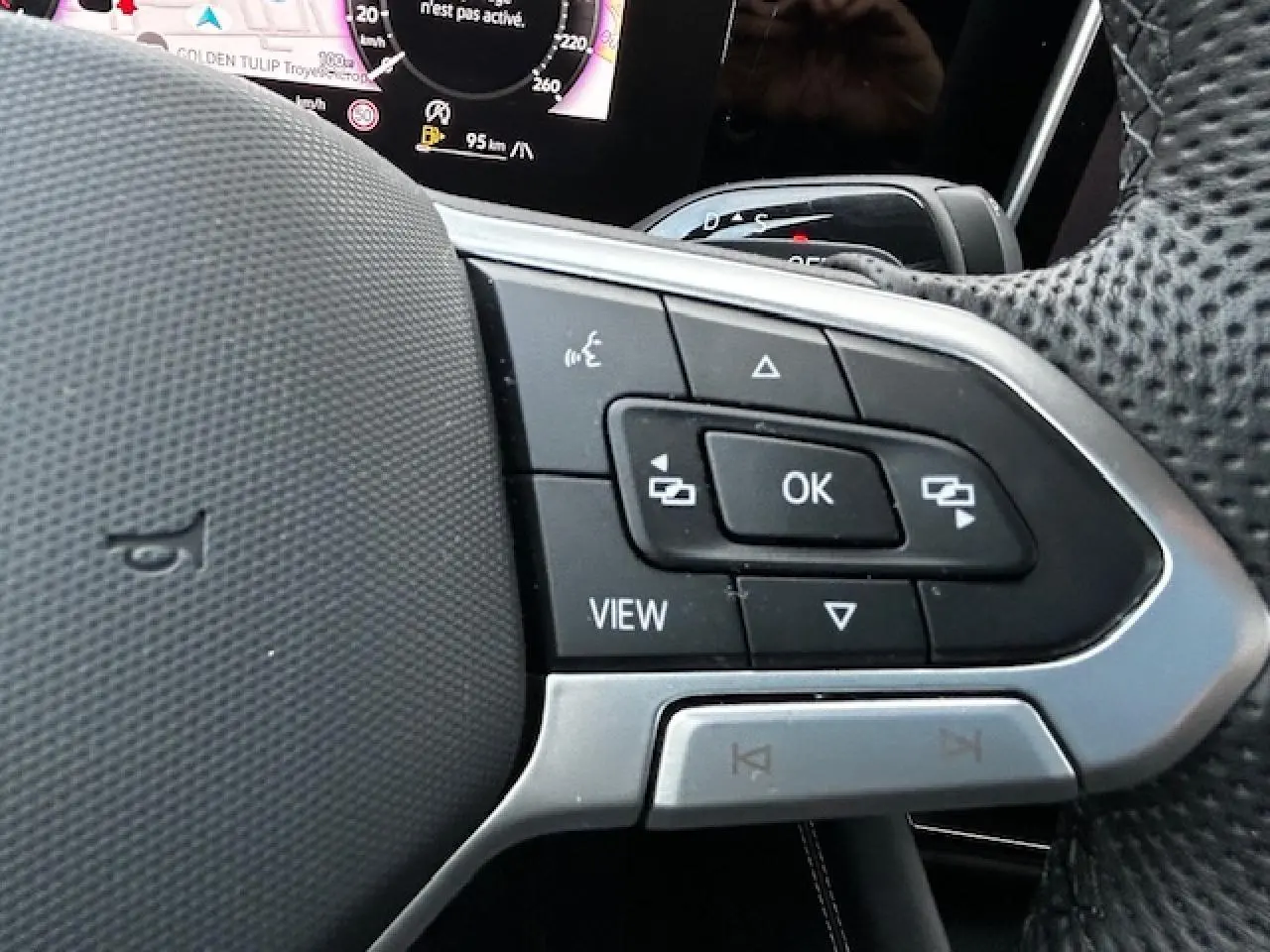 Gros plan sur les commandes multifonctions côté gauche du volant perforé du Volkswagen Tiguan gris clair 2024.