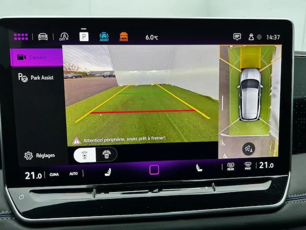 Écran tactile du Volkswagen Tiguan 2024 montrant la caméra de recul et l'assistance au stationnement avec vue aérienne du véhicule gris clair.