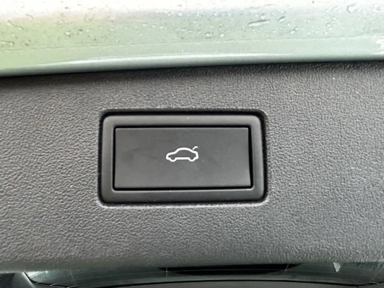 Bouton noir de déverrouillage du coffre sur la console intérieure du Volkswagen Tiguan gris clair 2024.